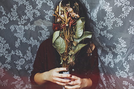 photography of woman covering her face with flowers