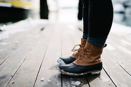 person in bean boots standing on brown wooden floor