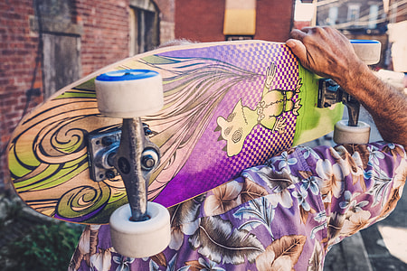 person holding purple and green cruiser board