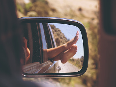 reflection of woman's feet in car side mirror