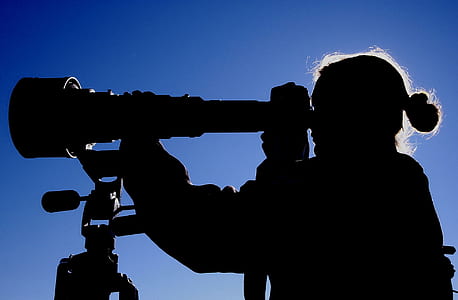silhouette photo of woman holding telescope