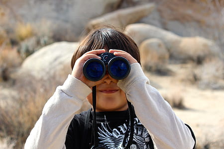 boy with black and white crew-neck long-sleeved shirt using black binocular scope during daytime
