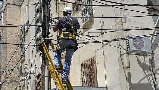 man in black shirt standing in yellow and black extension ladder
