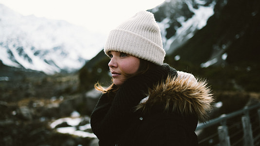 black haired woman in black parka jacket wearing white beanie in tilt shift photography