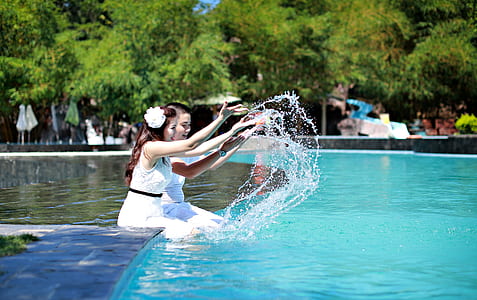two girls playing in swimming pool during daytime