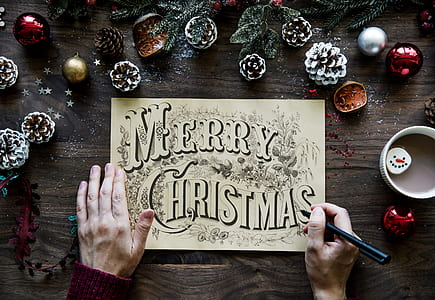 person writing Merry Christmas on white paper