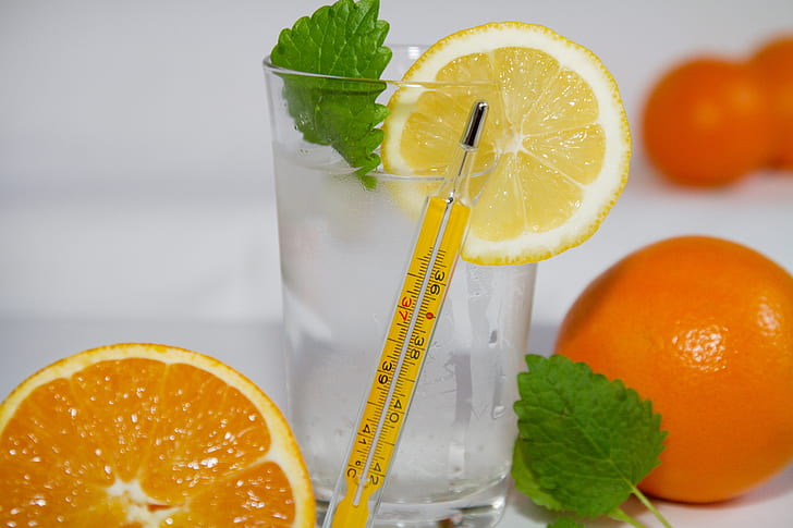 yellow thermometer beside glass of water with sliced lemon