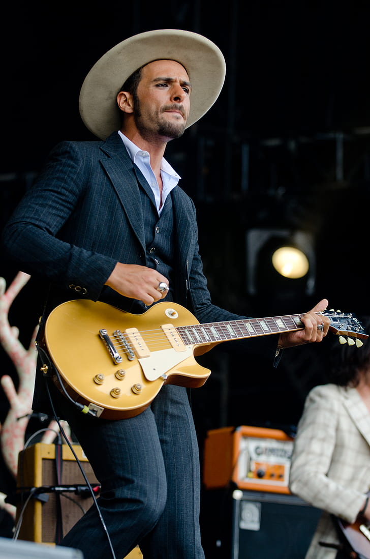 Man in Black and White Pinstripe Formal Coat and Pants Wearing Beige Hat Holding Brown Electric Guitar