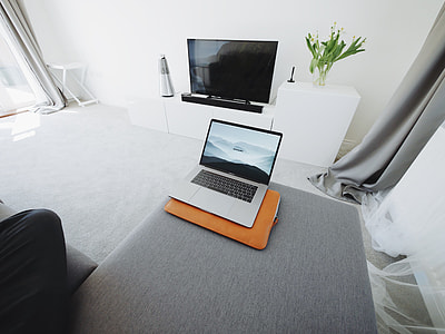 MacBook Pro on gray sectional sofa in white room
