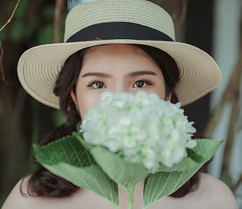 Woman Wearing White Hat Holding Flowers