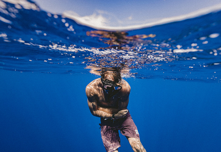 man in red shorts free diving in clear water under clear blue sky