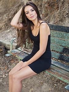 woman in black spaghetti-strap dress sitting on bench