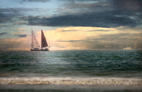 sail boat on body of water under cloudy sky