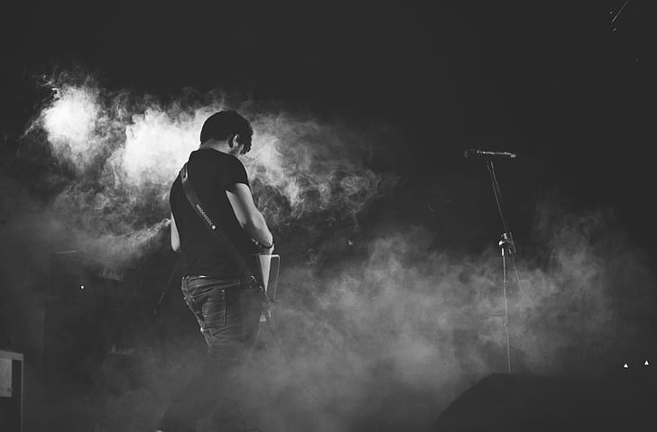 man standing on stage with white smokes photography