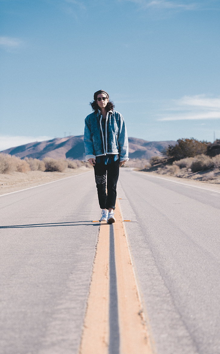 man standing on the middle of the road during day time