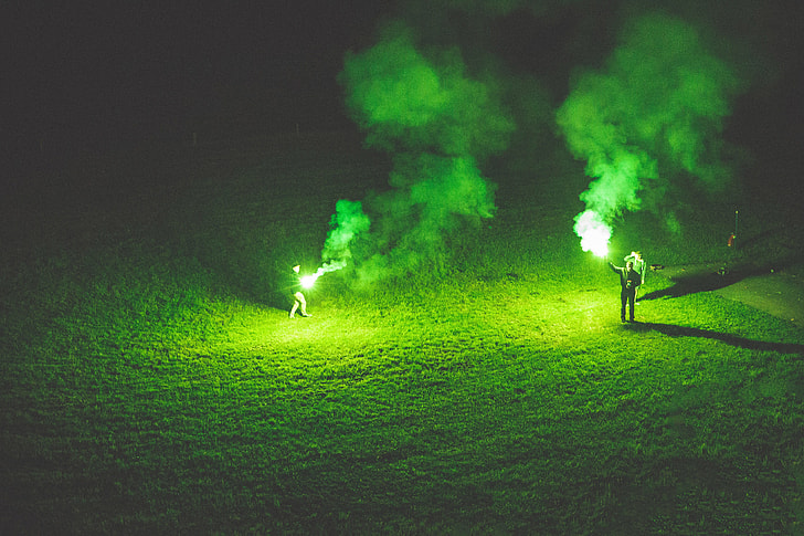 People holding green flares at night