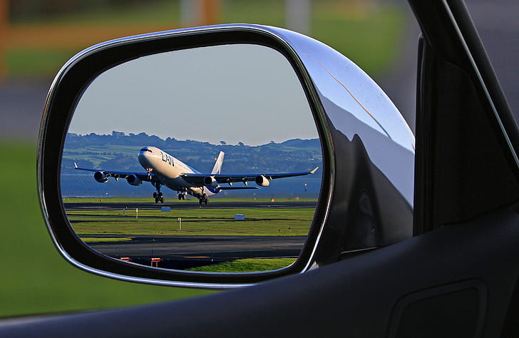 vehicle wing mirror reflect view of airliner about to fly during daytime