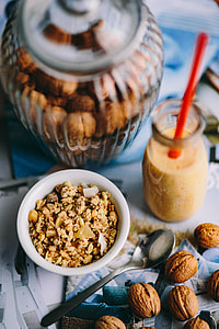 Jar full of walnuts with a fresh healthy shake and musli in a bowl