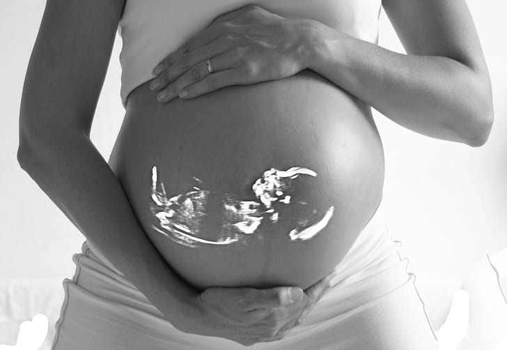 grayscale photo of woman holding her belly with baby