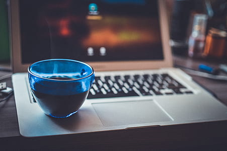 Blue Glass Cup on Silver Laptop Computer