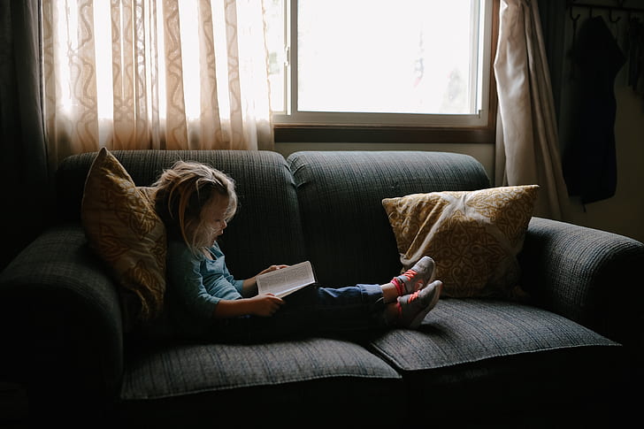 child sitting on couch infront of window