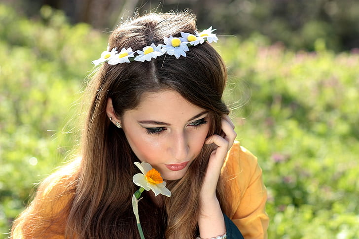 woman holding a white daffodil wearing flower headdress selective-focus photo