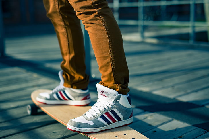 person wearing gray-white-and-red high-top sneakers on beige longboard