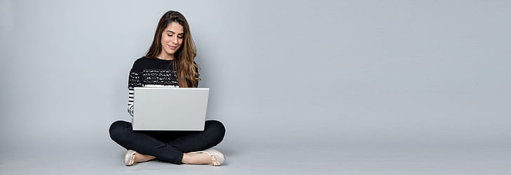 woman sitting in the floor while using white laptop