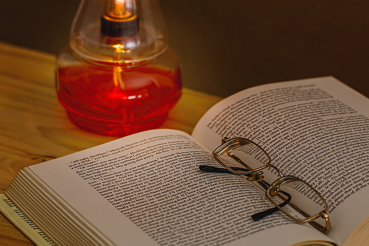 eyeglasses on a book near on fragrance bottle