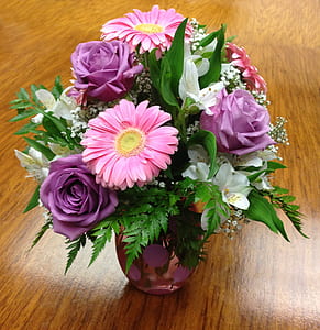 purple and pink petaled flower arrangement on brown wooden surface