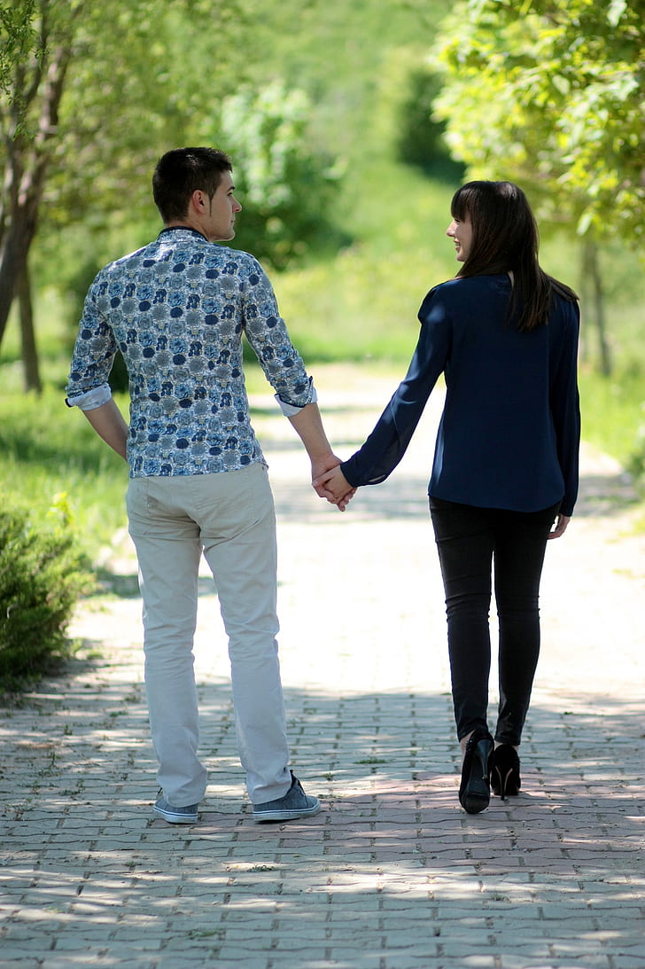 man and woman holding hands walking on road