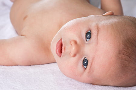 baby lying on white textile portrait photo