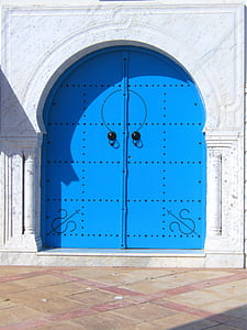 blue metal door on white concrete wall