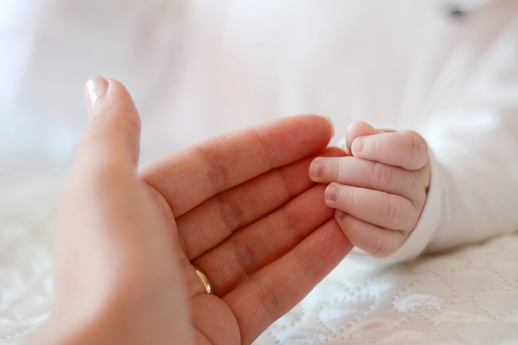 person's hand holding baby's hand