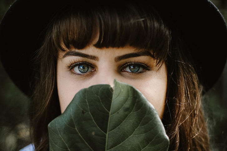 closeup photo of woman's face covered with green leaf