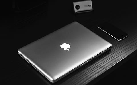 silver MacBook on table beside smartphone