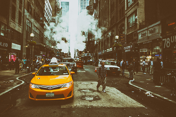 Street shot containing a yellow taxi cab on an overcast day in Midtown Manhattan in New York City
