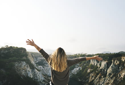 Woman With Blonde Hair at the Top of the Mountain Raising Her Hands