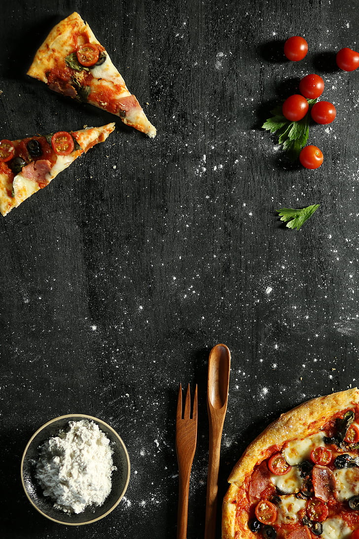 two slice of pizza near tomatoes and spoon