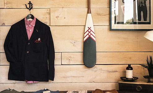 black suit jacket hanging near brown wooden wall