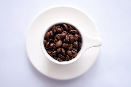 coffee beans on white ceramic mug and saucer