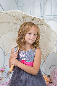 girl wearing gray sequin sleeveless dress holding beige umbrella