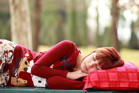 woman in red sweatshirt sleeping outdoor during daytime
