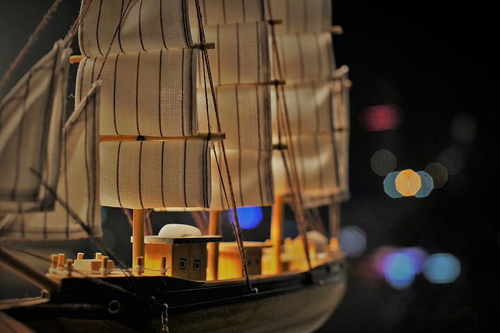 closeup photo of brown and black wood ship model with bokeh background