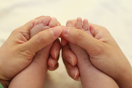 person hand holding baby's feet