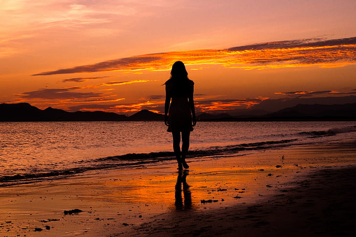 silhouette photograph of woman standing near sea shore