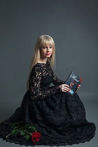 woman wearing black lace dress holding book looking on camera