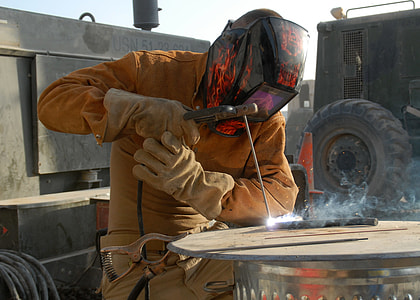 person wearing orange jacket and black welding mask during daytime