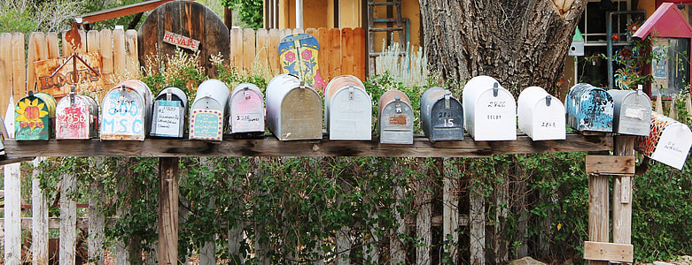 assorted-color mail boxes on wooden rack