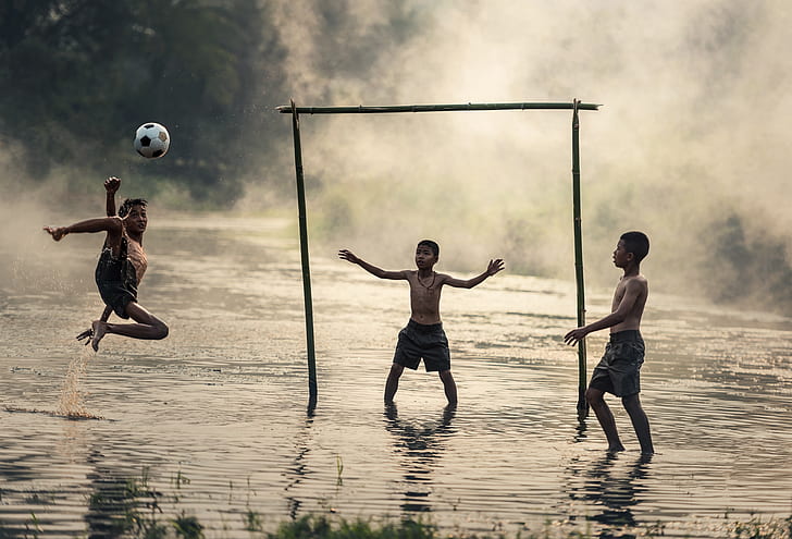 three boys playing soccer